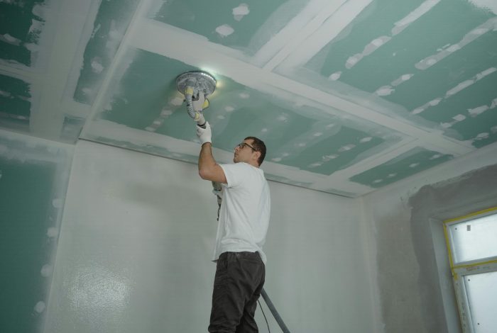 A worker expertly polishes a ceiling indoors, demonstrating home renovation skills.